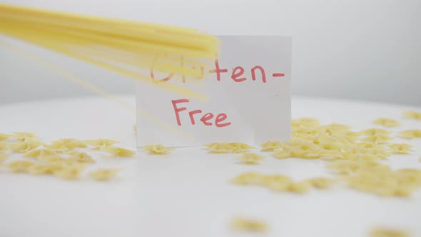 Glutenfree Pasta Farfalle on Table with Spagetti Falling in Slow Motion alt