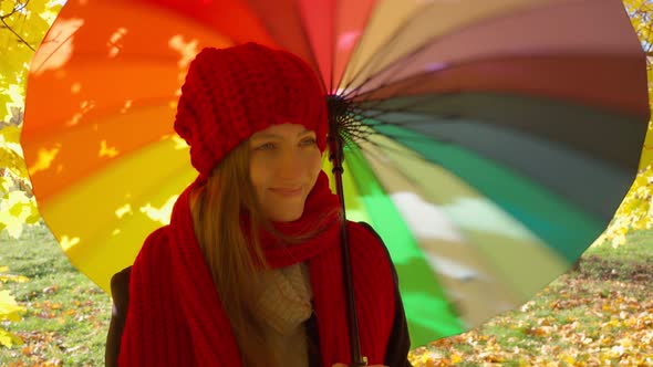Beautiful Happy Woman Stands with an Umbrella in the Park and Smiles
