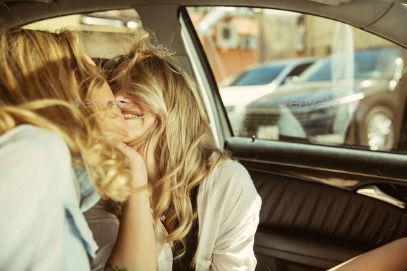 Young lesbian's couple preparing for vacation trip on the car in sunny day - Stock Photo - Images