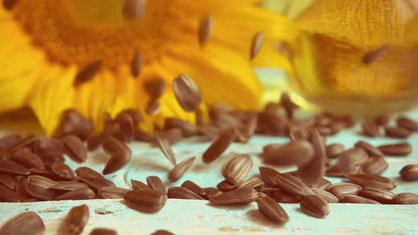 Sunflower, sunflower oil on blue vintage wooden table top and falling sunflower seeds on it alt