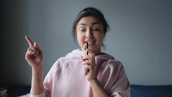 happy indian woman singing at home having fun celebrating successful lifestyle dancing enjoying 