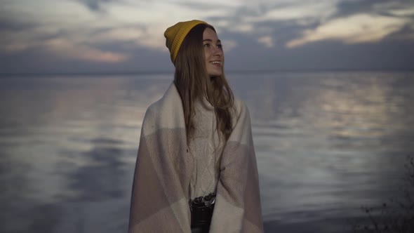 Portrait of Happy Young Caucasian Woman in Yellow Hat and Blanket Looking Around Admiring Beauty of alt