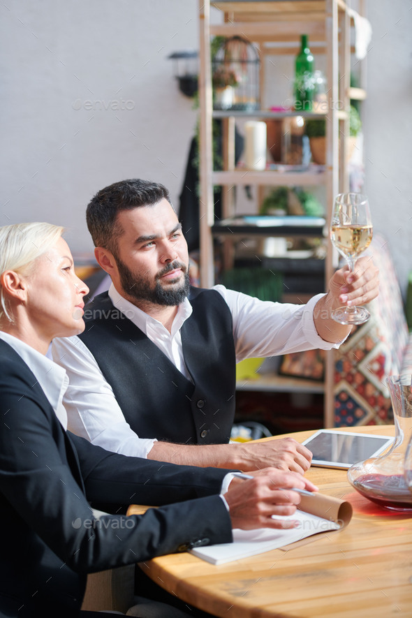 Two colleagues consulting about characteristics of one of wine samples - Stock Photo - Images