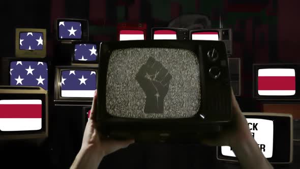Hands rising Old TV Set with Clenched Fist on its Screen over American Flag. alt