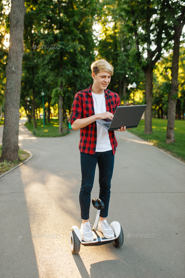 Young man riding on mini gyro board with laptop