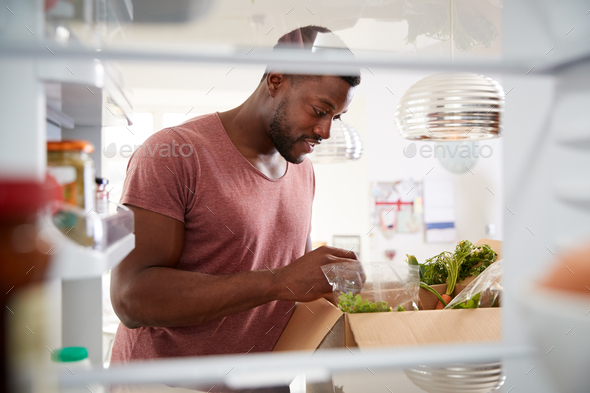 View Looking Out From Inside Of Refrigerator As Man Unpacks Online Home Food Delivery