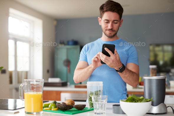 Man Using Fitness Tracker To Count Calories For Post Workout Juice Drink He Is Making