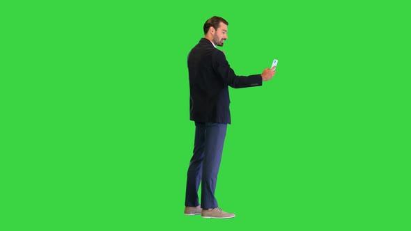 Attractive Business Man Is Making a Selfie on a Green Screen Chroma Key alt
