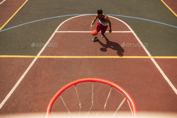 Young professional basketball player with ball running down court