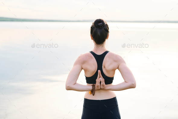 Rear view of young woman with strengthened spine standing against sea