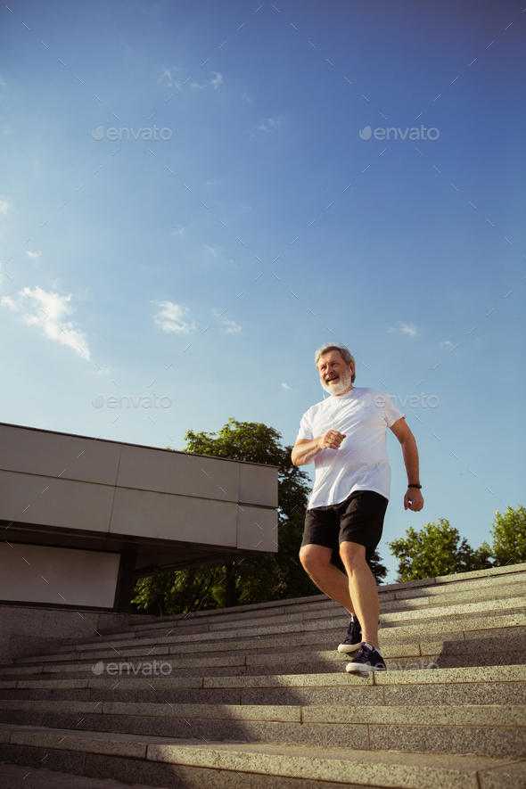 Senior man as runner with armband or fitness tracker at the city's street