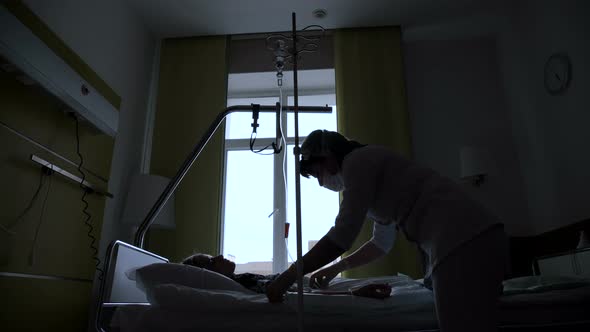 The Silhouette of a Nurse Makes Intravenous Medication To the Patient alt