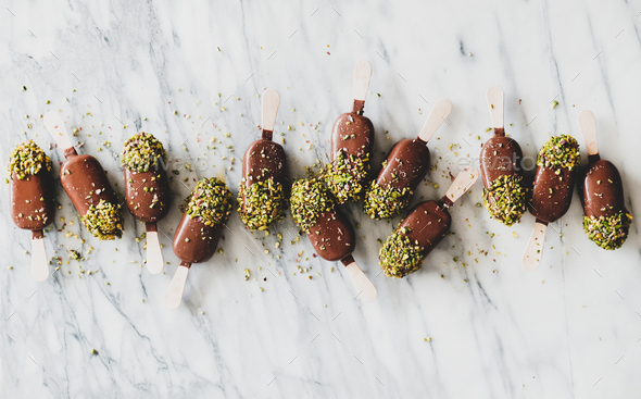 Flat-lay of chocolate glazed ice cream pops with pistachio - Stock Photo - Images