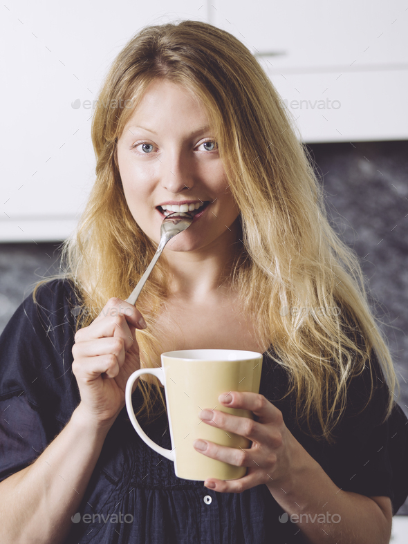 Beautiful blond having coffee in her kitchen - Stock Photo - Images