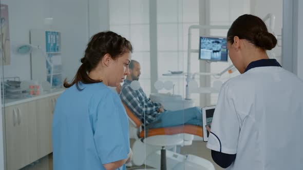 Dentistry Team Discussing Procedure Using x Ray on Tablet alt