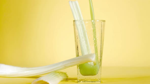 Delicious organic celery juice is poured in glass on a yellow colored background alt