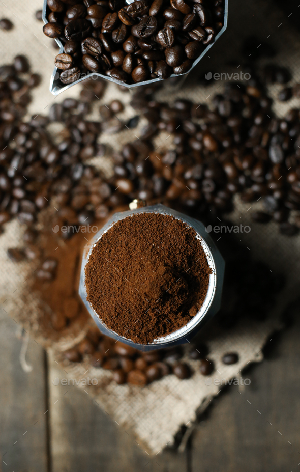 Coffee beans ground coffee in mokapot with wood background