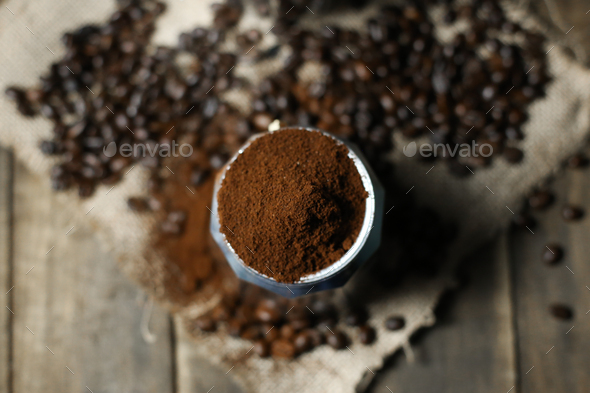 Coffee beans ground coffee in mokapot with wood background