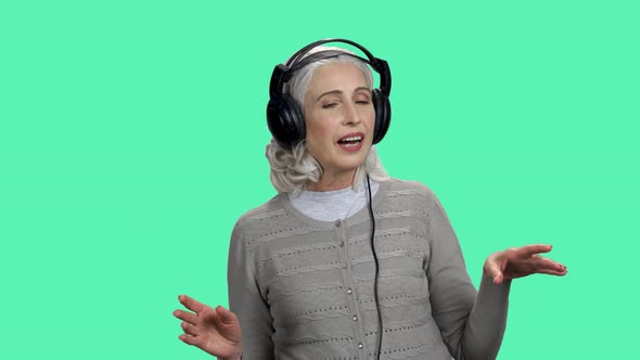 Relaxed Senior Woman Listening To Music on Color Background alt