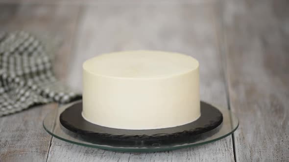 Homemade White Cream Cake on a Rotating Stand in a Home Kitchen
