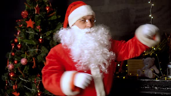 Modern Santa Claus dancing near the Christmas tree .