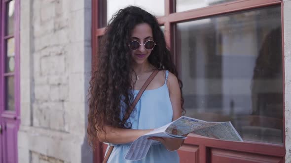 Young Smiling Woman Tourist Reading Map on Vacations in Europe