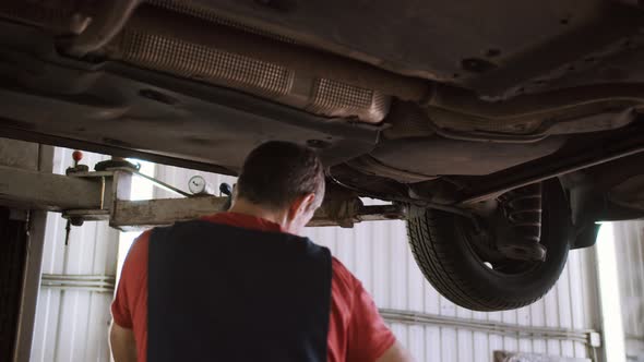 Auto Mechanic Repairs Car on the Lift in the Service Station