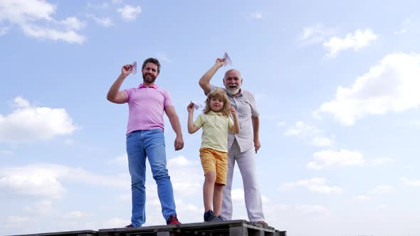 Happy Family of Boy Son and Old Man Grandfather Hold Paper Planes Standing Skyhigh Freedom alt