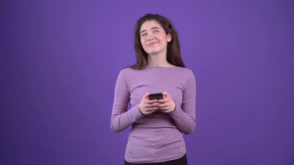 The Charismatic Young Woman Writes a Message on the Phone Concentrated and with a Smile in Love alt