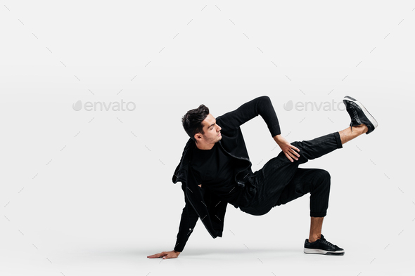 Handsome young man wearing a black sweatshirt and black pants is dancing breakdance doing dancing
