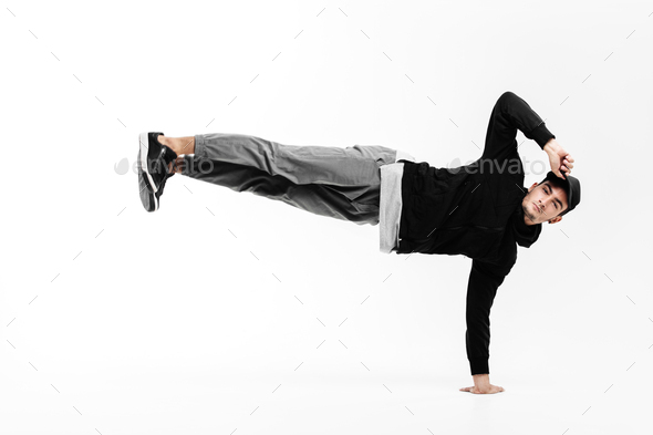 Stylish young man is dancing breakdance. He is standing on one arm and lifting both legs up