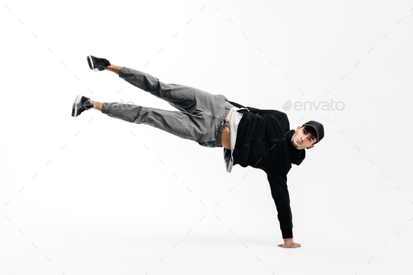 Stylish young dancer is dancing breakdance. He is standing on one arm and lifting both legs up