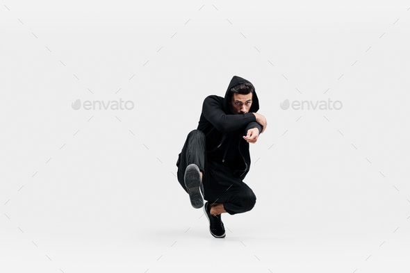 Handsome young dancer wearing a black sweatshirt and black pants is dancing breakdance doing dancing