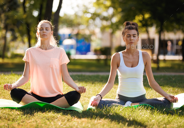 Women doing yoga outdoors at sunrise. Morning meditation