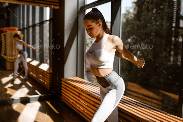 Slim young dark-haired girl dressed in white sports clothes doing