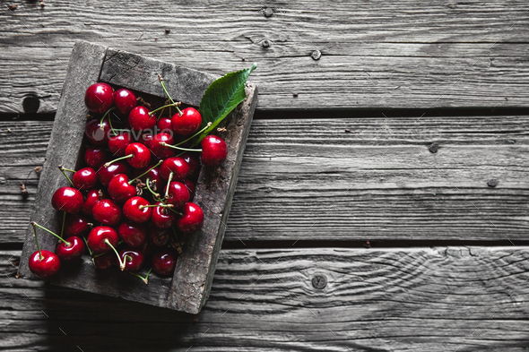 Cherries in a wood crate over a wood background in an old wooden box, healthy food, fruit
