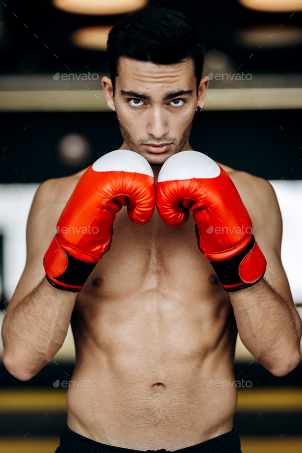 Sportsman With A Naked Torso Keeps His Hands In The Red Boxing Gloves Next To His Face In The