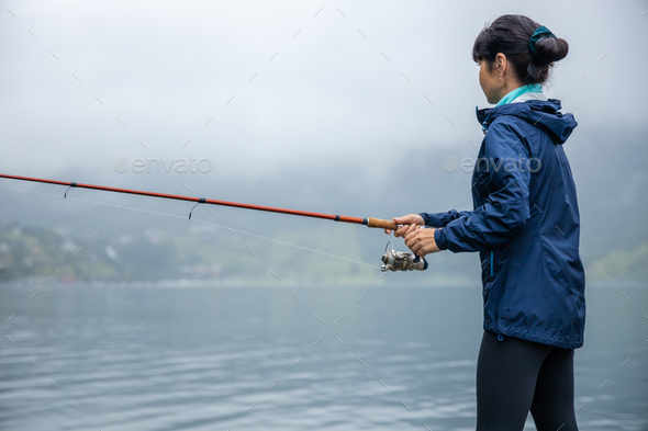 Woman fishing on Fishing rod spinning in Norway. Stock Photo by