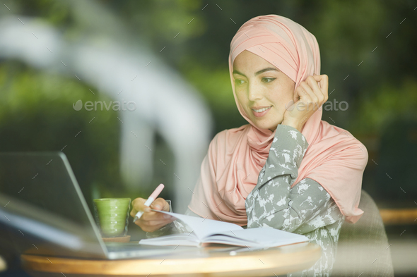 Woman in hijab watching webinar - Stock Photo - Images
