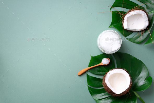 Tropical monstera leaves, ripe coconuts, coconut oil on green background  with copy space. Top view Stock Photo by jchizhe