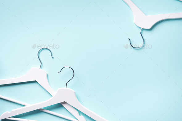 Top view of white clothes hangers on blue background with copy space. Flat  lay. Minimalism style Stock Photo by jchizhe