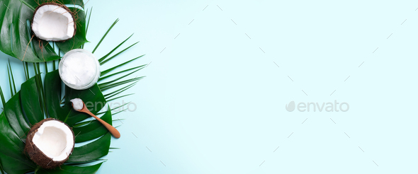 Tropical monstera leaves, ripe coconuts, coconut oil on blue background  with copy space. Top view Stock Photo by jchizhe