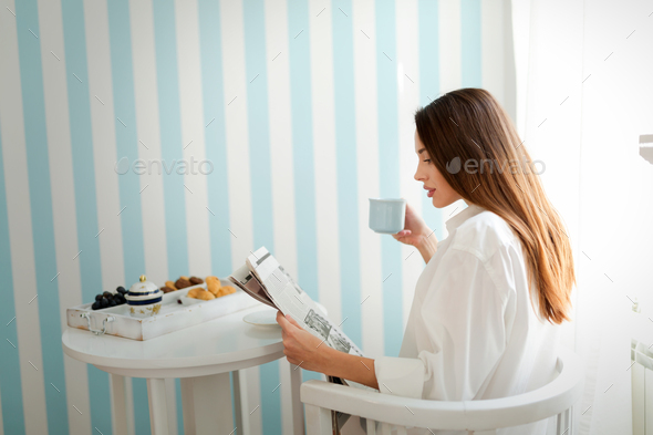 Young woman with cup of coffee sitting at table - Stock Photo - Images
