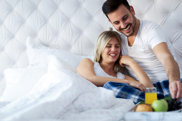 Young attractive couple having breakfast in bed - Stock Photo - Images