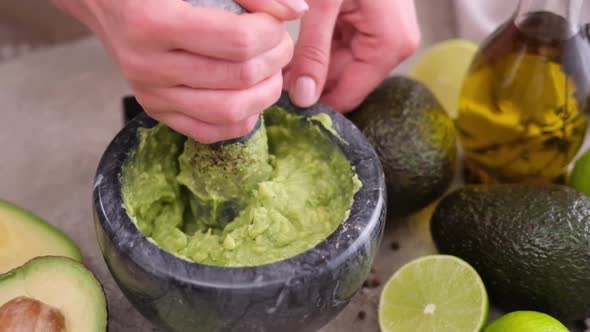 Making Guacamole Sauce  Woman Mashing Avocado in a Marble Mortar with Pestle at Domestic Kitchen alt