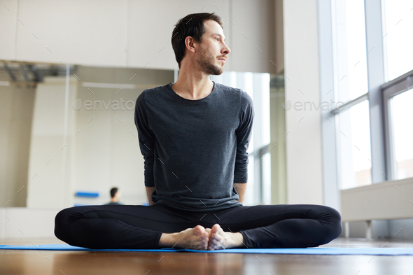 Flexible man sitting inbound angle pose - Stock Photo - Images