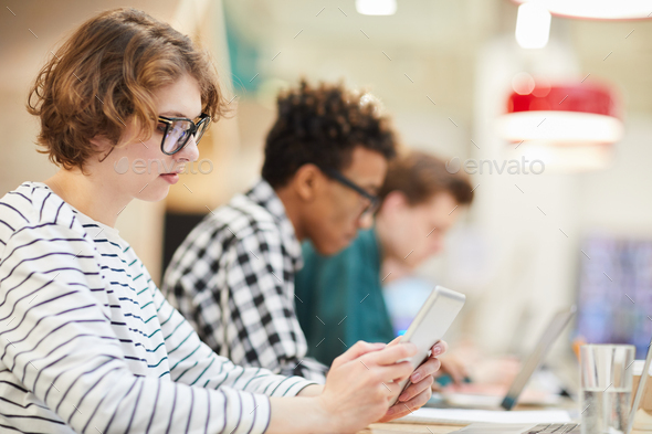 Thoughtful student girl using tablet in university - Stock Photo - Images