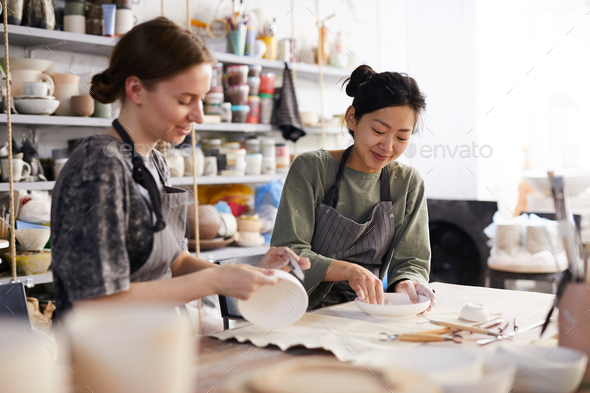 Positive women processing dishes in workshop - Stock Photo - Images