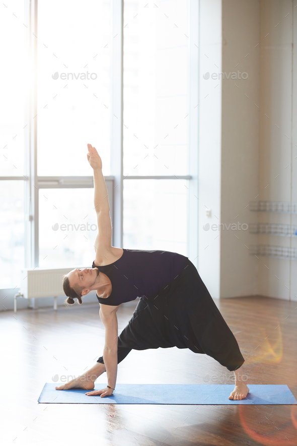 Performing extended triangle pose - Stock Photo - Images