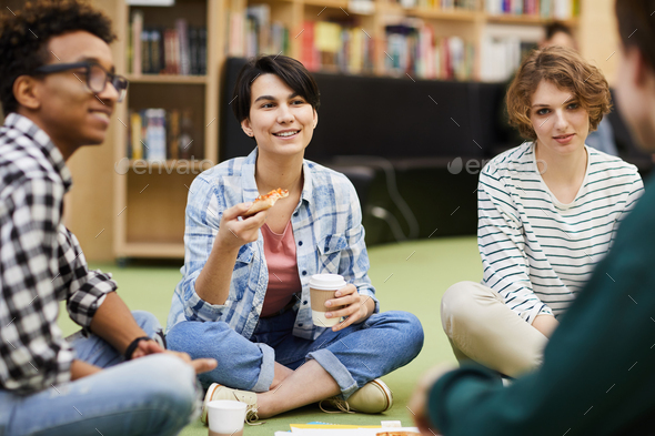 Positive students having lunch break in library - Stock Photo - Images